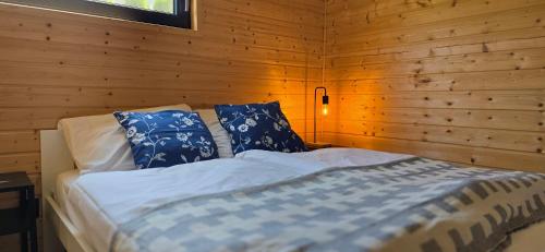 a bedroom with a bed with blue and white pillows at Piaski Rogowa in Rogowo