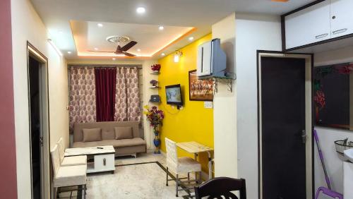 a living room with a couch and a yellow wall at Homely Stay in Kolkata