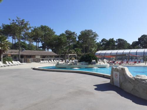 une grande piscine avec des chaises et un bâtiment dans l'établissement Mobil-home dans camping 5 etoiles en bord de plage, à Montalivet-les-Bains