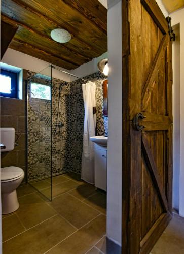 a bathroom with a shower toilet and a glass door at Halháza vendégház in Sirok