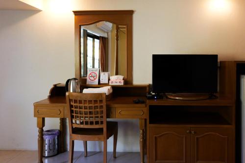 a desk with a television and a mirror at โรงแรมมูนแอนด์ซัน Moon and Sun Hotel in Chiang Rai