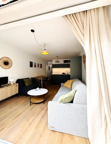 een woonkamer met een witte bank en een tafel bij Appartement Chic 50m de la mer in Palavas-les-Flots