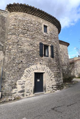- un grand bâtiment en pierre avec une porte latérale dans l'établissement la tour du forgeron, à Rochefort-en-Valdaine