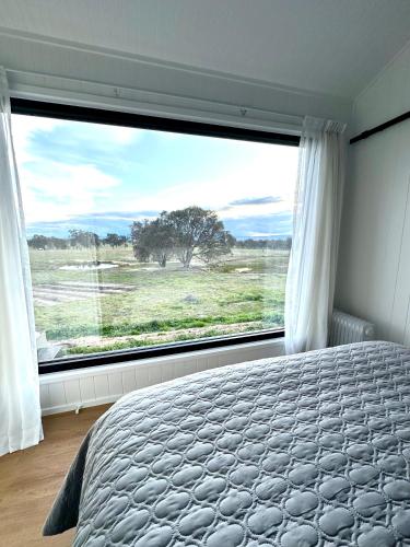 a bedroom with a bed and a large window at Belle Barn in Murrumbateman