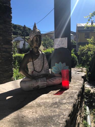 a statue of a woman sitting on a wall with a red candle at Casa Cantadora in Ambasmestas