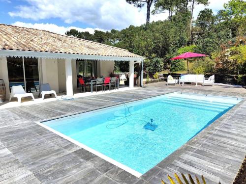 une piscine devant une maison dans l'établissement Villa spacieuse avec piscine chauffée, jardin et terrasse à Petit-Piquey - FR-1-736-9, à Lège-Cap-Ferret