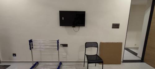a black chair and a tv on a white wall at Kalyan PG & Boys Hostel in Gandhinagar