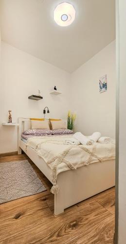 a bedroom with a bed with a white wall at Hana Plitvice Apartment in Korenica