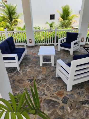 a patio with chairs and a table and palm trees at Room for 2 w kitchen pool close to the beach in Las Galeras