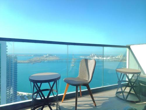 two chairs and two tables on a balcony with a view of the ocean at Full Seaview & Louvre Museum 1BHK - Al Reem Island in Abu Dhabi
