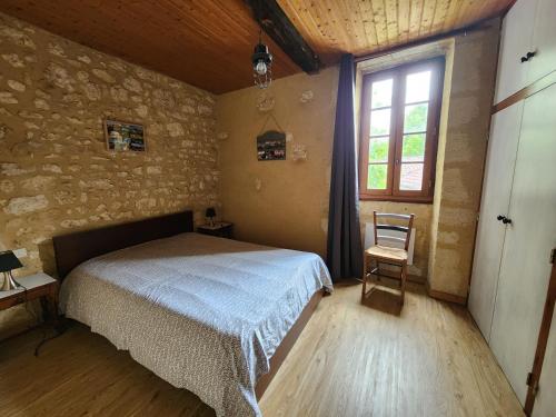 une chambre avec un lit, une fenêtre et une chaise dans l'établissement Maison en pierre Chez Sorel, à Couze-et-Saint-Front