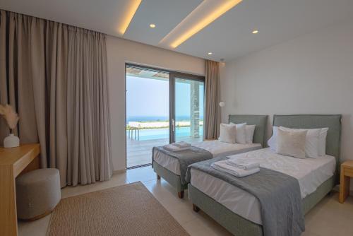 a bedroom with two beds and a view of the ocean at Lamar Private Luxury Villas in Marathias