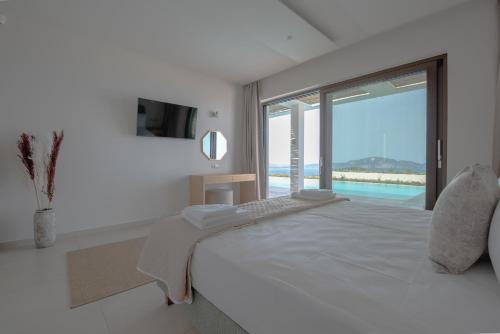 a white bedroom with a large bed and a large window at Lamar Private Luxury Villas in Marathias