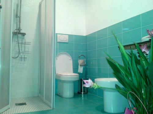 a blue tiled bathroom with a toilet and a sink at Friulmarangon in Basiliano