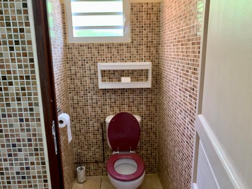 a small bathroom with a red toilet and a window at Gîte chez Marie in Saint-Claude