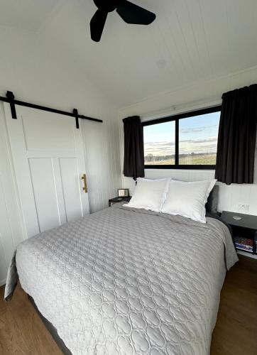 a bedroom with a white bed with a large window at Belle Barn in Murrumbateman