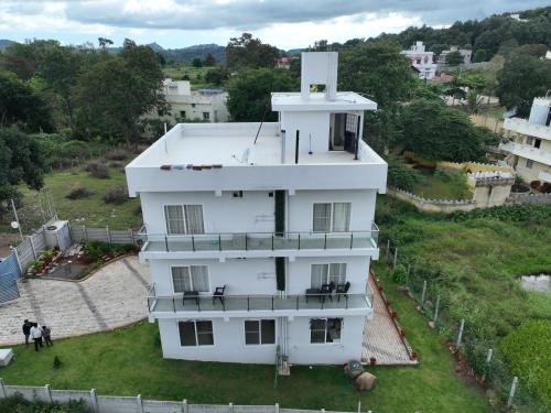 a white building with people standing around it at PRS CREEK SIDE HOME STAY VILLA in Yelagiri