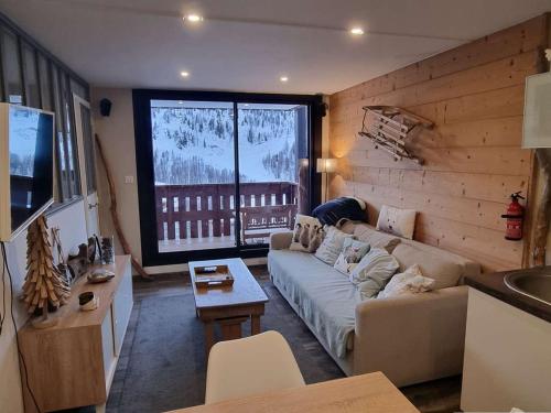 un salon avec un canapé et une grande fenêtre dans l'établissement Appartement rénové au calme avec balcon, 1 chambre, coin nuit et parking - Proche Isola 2000 - FR-1-292-137, à Isola 2000