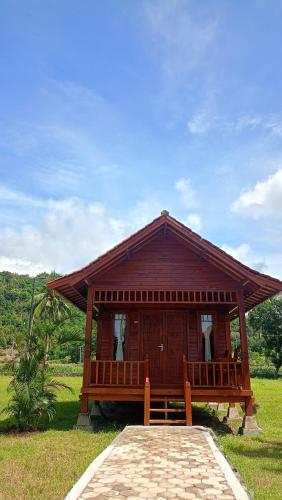a small wooden house with a porch in a field at Mio Villa Tomang Omang Lombok in Selong Belanak