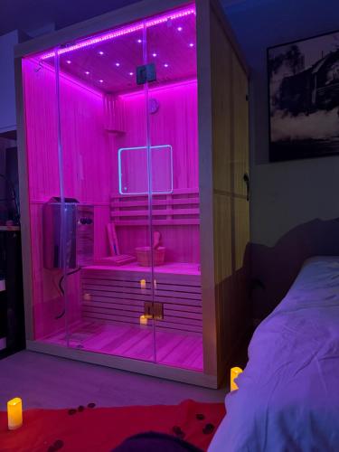 une chambre avec des lumières roses dans une chambre avec un lit dans l'établissement Love room nantais, à Nantes