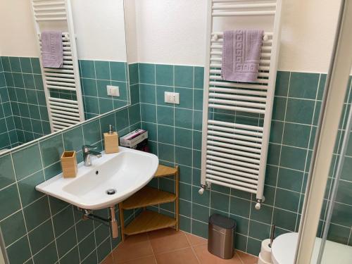 a bathroom with a white sink and green tiles at Appartamento Pitosforo e Camera Melograno in Leivi