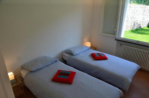 two beds in a room with red pillows on them at Appartamento Pitosforo e Camera Melograno in Leivi