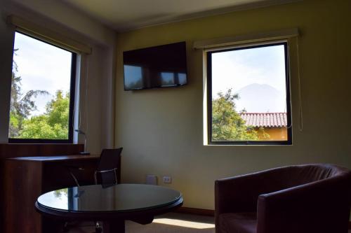 a waiting room with a table and two windows at Hotel Villa del Carmen in Arequipa