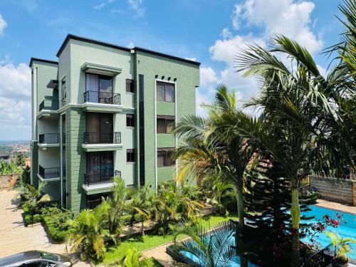 a green building with palm trees and a swimming pool at Bellwether Apartments in Kampala