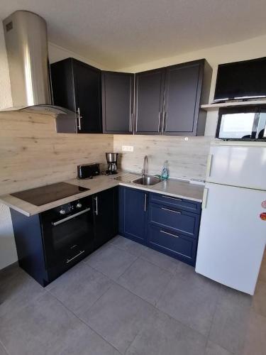 - une cuisine avec des armoires noires et un réfrigérateur blanc dans l'établissement Appartement vue mer 