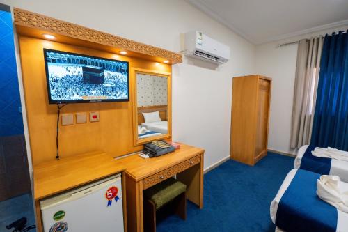 a room with a tv and a desk with a mirror at فندق زاد المجد مكة الروضة in Makkah