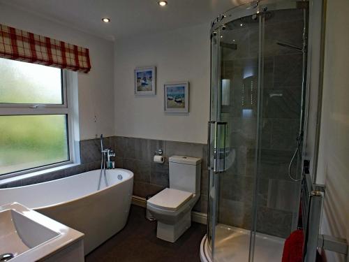 a bathroom with a tub and a toilet and a shower at The Old Vicarage in St Austell