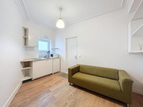 un salon avec un canapé vert et une cuisine dans l'établissement L'Instinct - Centre-Ville - Métro Paris, à Levallois-Perret