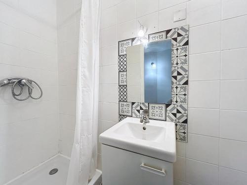 une salle de bain blanche avec un lavabo et un miroir dans l'établissement L'Instinct - Centre-Ville - Métro Paris, à Levallois-Perret
