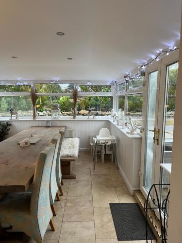 una camera con un lungo tavolo, sedie e finestre di Goleufryn Abersoch has the main house and 2 barns ad Abersoch