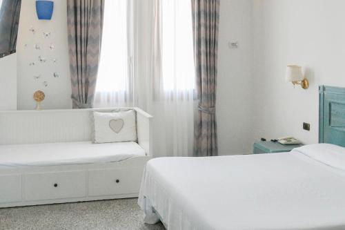 a white room with two beds and a window at L'incanto Di Boccadarno in Marina di Pisa