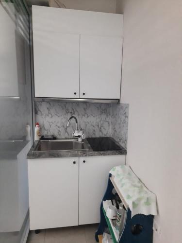 Endi City Centre Room في تيرانا: مطبخ بخزائن بيضاء وحوض غسيل