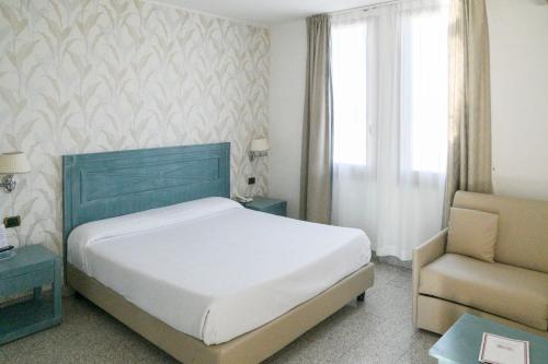 a bedroom with a bed and a chair and a window at L'incanto Di Boccadarno in Marina di Pisa