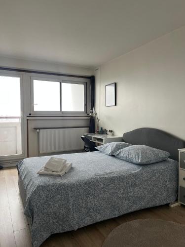 une chambre avec un lit et un bureau et deux fenêtres dans l'établissement Quarto Privado em Apartamento Vista Torre Eiffel, à Paris
