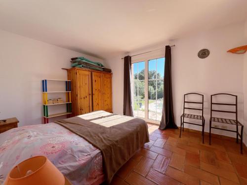 une chambre avec un lit et deux chaises et une fenêtre dans l'établissement Villa La Mastineria, au Plan-de-la-Tour