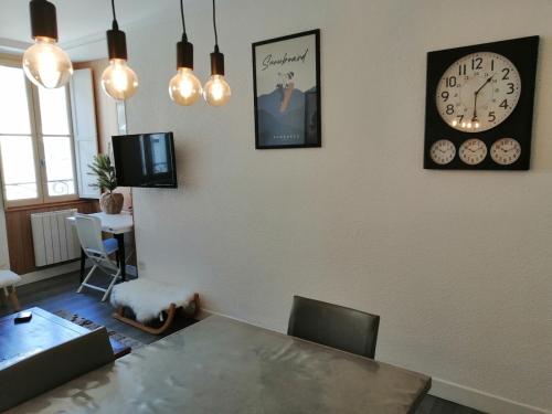 une salle à manger avec une table et des horloges murales dans l'établissement Cauterets et son bel appartement, à Cauterets