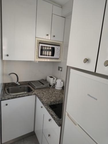 a kitchen with white cabinets and a microwave at Apartamento Exclusivo en la Playa 9 in Benidorm