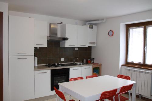 une cuisine avec des placards blancs et une table et des chaises blanches dans l'établissement Alpini Apartments, à Chiesa in Valmalenco