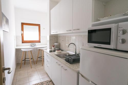 a white kitchen with a microwave and a sink at Apartman Krtalić in Međugorje