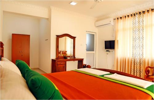 a bedroom with an orange bed and a mirror at Ronaka Airport Transit Hotel in Katunayake