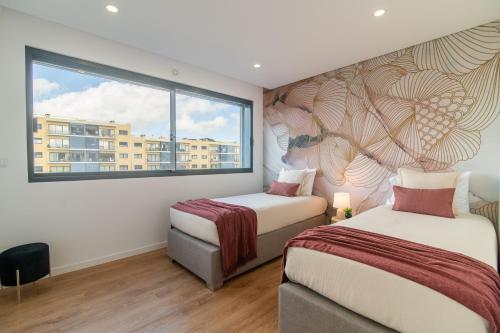 two beds in a room with a window at Priolo in Ponta Delgada - 4th floor apartment in Ponta Delgada