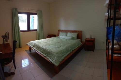 a bedroom with a bed with green sheets and a window at Casa Shanti in Nusa Dua
