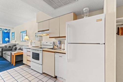 a kitchen with a white refrigerator and a couch at Yachtsman Oceanfront Resort in Myrtle Beach