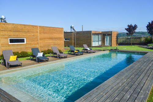 a swimming pool with chairs and a house at Óbidos Wood Villas in Olho Marinho