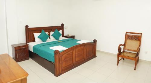 a bedroom with a wooden bed and a chair at Ronaka Airport Transit Hotel in Katunayake