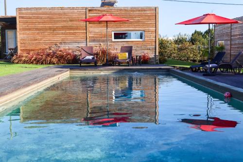 a swimming pool with two chairs and an umbrella at Óbidos Wood Villas in Olho Marinho